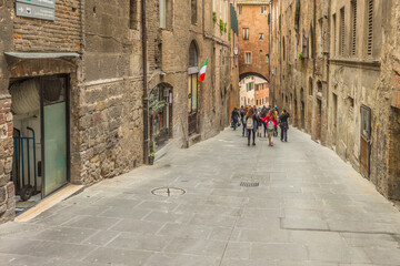 Fototapeta premium Old street in the historical center of Siena, the UNESCO World Heritage Centre unchanged for 13-14 centuries, with its medieval streets looked like in the early Middle Ages. Italy, 2019 