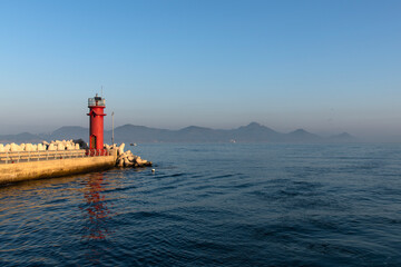 lighthouse on the jetty with fog on the sea in the morning