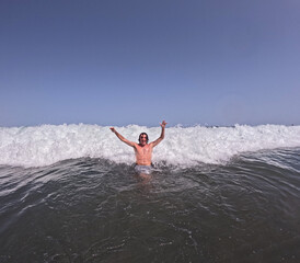 young man playing on the beach with the waves of the sea