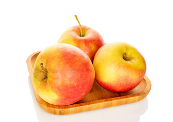 Three sweet apples on a bamboo plate, close-up, isolated on a white background.