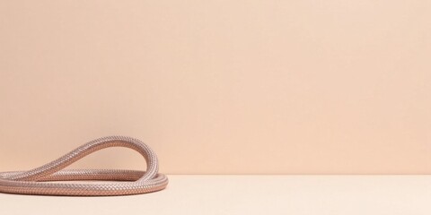 Naklejka premium Elegant Rose Gold Cord on Neutral Background, Minimalist Product Photography Concept