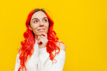 red-haired woman smiling and looking away on yellow isolated background, girl with colored curly hair looking at copy space