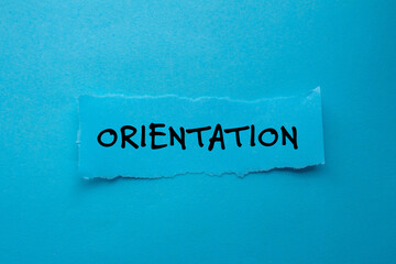 Orientation message written on ripped torn paper piece on blue background. Conceptual orientation symbol. Copy space.