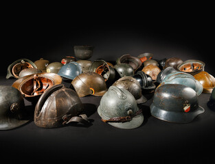 Obraz premium Sammlung historischer Militärhelme aus verschiedenen Epochen als Relikte vergangener Kriege und militärischer Traditionen auf schwarzem Untergrund mit dramatischer Belechtung