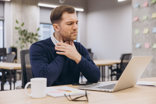 Businessman experiencing neck discomfort while working at office desk
