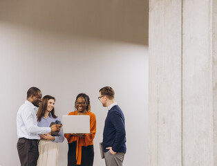 Diverse professional team collaborating, analyzing laptop project with engaged expressions in...