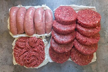 Barbecue mixture, burgers, sausages, and minced beef on a concrete table. Top view.