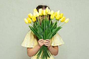 Girl holding yellow tulips against light background with delicate springtime vibes