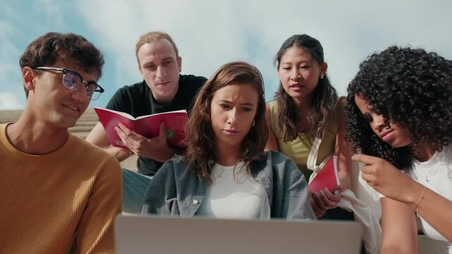 Friendly group of multiracial high-school students using computer technology. Low angle