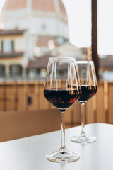 Tasting of local red wine on sunny summer balcony in Florence, Italy. Two glasses of red vine on the table. Cathedral Santa Maria del Fiore in Tuscany, Florence