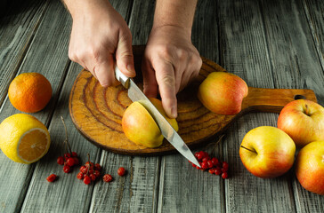 Hands expertly slice an apple while vibrant fruits surround a rustic wooden board. Citrus and...