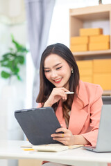 businesswoman running SME business and preparing stock for delivery through reliable logistics and receiving orders through online application promoting sales by promoting shop through online media