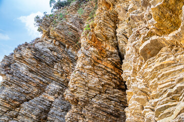 Layered rock texture in Budva, Montenegro. Sedimentary rocks with rugged surface of gray and brown....