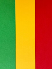 A bold and colorful abstract arrangement of green, yellow, and red paper strips forming a vertical striped pattern.