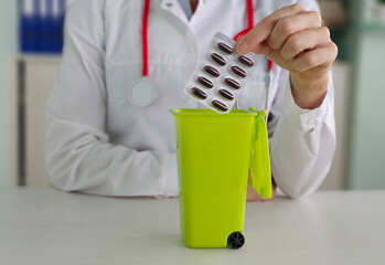 Doctor throws medicines into green trash bin during consultation concept