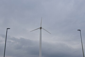 a wind turbine with three blades against a cloudy sky. Wind turbines generate renewable energy by converting wind power into electricity, essential for sustainable energy solutions.