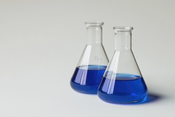 Two clear glass flasks filled with a bright blue liquid