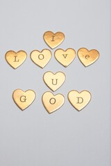 gold heart-shaped objects arranged to spell "I LOVE U GOD" on a gray background. © Elvis
