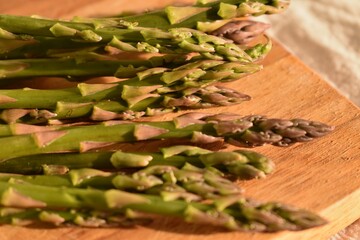 Green fresh asparagus from the garden lies on a wooden board on the table