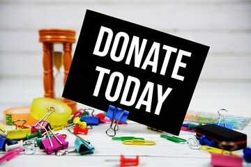 Donate Today text on paper card with stationary on wooden background
