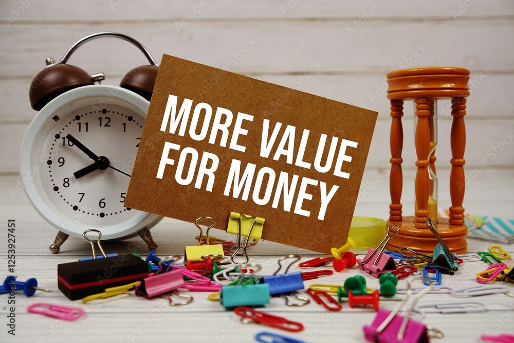 Poster more value for money text on paper card with alarm clock and stationary on wooden background