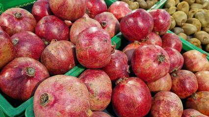 Ripe pomegranate fruits for sale in a supermarket. Pomegranate fruits close-up with selective focus. Berry-like fruit. Pile of delicious pomegranates for sale in a store. Variety of fresh produce