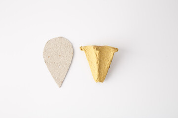 a light beige teardrop-shaped piece of material and a yellow three-dimensional cone shape, a piece...