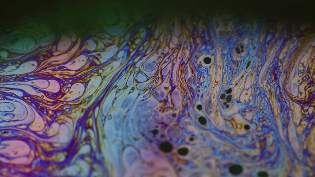Acrylic spray. Bubbles wave. Defocused multicolor purple green liquid oil paint curve acrylic slick on dark black blurred light abstract art background.