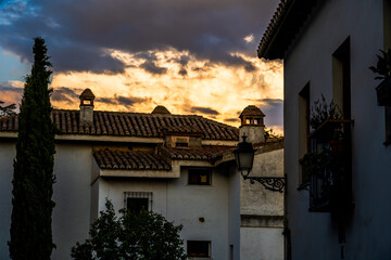 Dramatic Dusk Over Granada Rooftops, Clay Chimneys, and White Facades Beneath Fiery Clouds Showcasing Moorish Influences in Andalusian Spain
