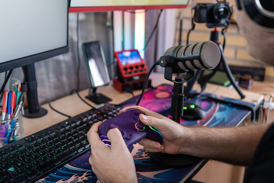 Gamer streaming live, holding controller, gaming setup, microphone and camera