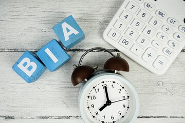 BIA (Business Impact Analysis) alphabet letters with alarm clock on wooden background