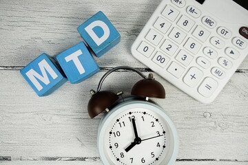 MTD (Month To Date) text with alarm clock and calculator on wooden background