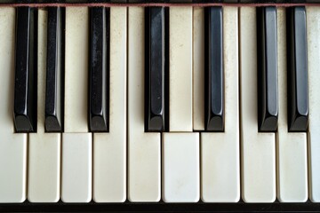 Naklejka premium Close-up of piano keys showcasing the aged beauty and timeless elegance of the instrument's monochrome pattern.