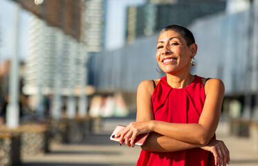 Confident woman in red top holding a smartphone outdoors