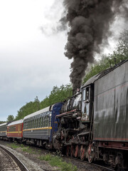 Naklejka premium Steam train is traveling down the tracks with smoke coming out of the engine