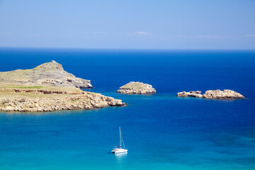 Turquoise waters and a sailboat in Lindos, Rhodes, Greece. A stunning Mediterranean seascape...