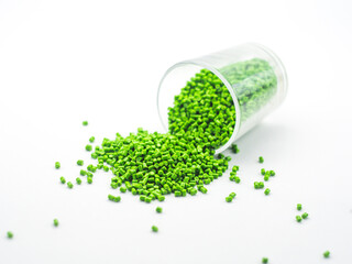 Green masterbatch granules spilling from glass cup,isolated on white background,color pigment...