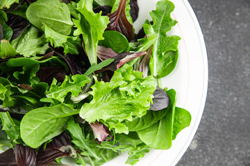 Healthy salad leaves mix salad juicy snack micro greens, arugula, lettuce, oak leaf, green leaf salad fresh tasty food background on the table rustic food top view copy space vegetarian and vegan