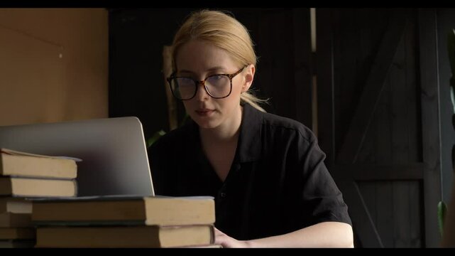 middle-aged white woman, a developer, is searching for a job during a crisis while sitting at a table at home with a laptop.