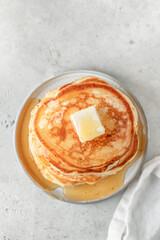 Homemade pancakes with honey an butter on top on gray kitchen table background top view. Pancake day traditional meal