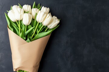 A beautiful bouquet of white tulips wrapped in brown paper against a dark background.