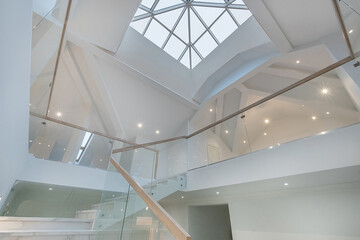 Fototapeta premium A stunning interior showcases an expansive glass dome allowing natural light to flood the area. An elegant staircase leads to an upper level, enhancing the open and airy feel.