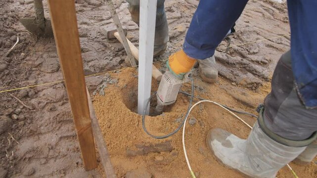 A dedicated worker is performing groundwork needed for the installation of structural support in muddy conditions