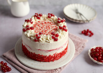 Red Velvet Cake with mascarpone and whipped cream on a plate, decorated with red currant. Pink...