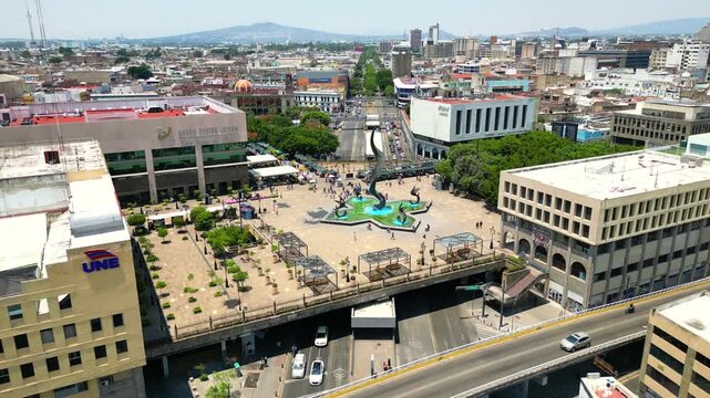 A dynamic drone shot advancing towards the Quetzalcoatl Fountain at Plaza Tapatia from the surrounding streets in Guadalajara
