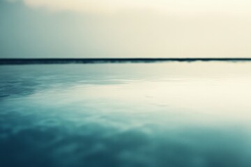 Fototapeta premium A serene, expansive water surface reflects a tranquil sky, blending shades of blue and grey for a dreamy, peaceful ambiance.
