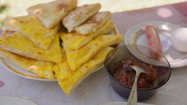 Sun-drenched outdoor stage with hearty homemade breakfast with golden amlet, khachapuri, freshly baked bread, crispy pastries, bright sauces, steaming coffee and aromatic tea