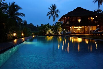 Fototapeta premium Serene Nighttime Retreat: Luxurious Holiday Villa with a Glimmering Pool Under the Stars