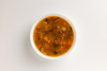 A top view of a round white bowl filled with summer vegetable minestrone, set against a white background. Simple, clean design, perfect for food styling, product mockups, or promotional use.
