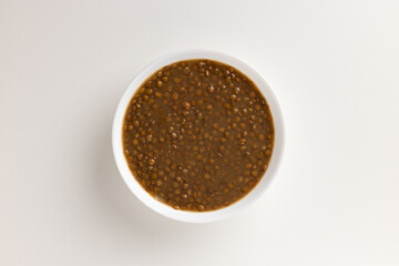 A top view of a round white bowl filled with lentil soup, set against a white background. Simple, clean design, perfect for food styling, product mockups, or promotional use.
